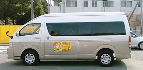 Brown shuttle van with NICONICO Rent a Car logo on the side.