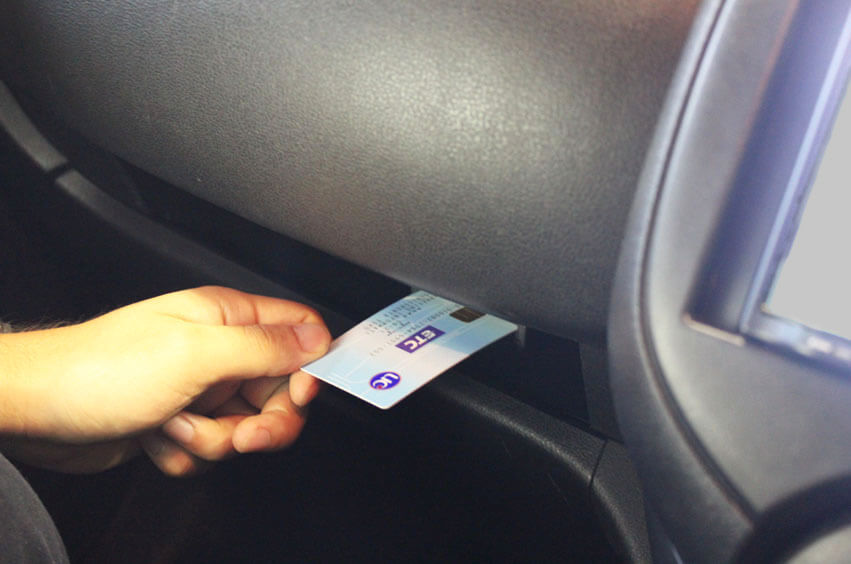 A person inserting an ETC card into the ETC reader inside of a car 九州高速公路KEP卡介紹