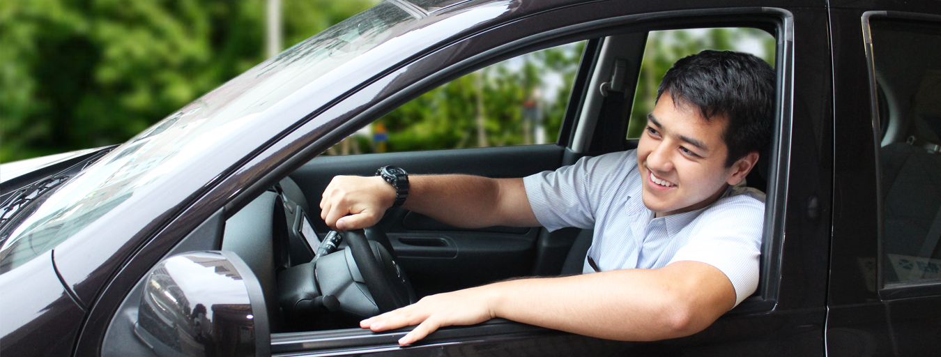 Young man reversing a purple car with his arm sticking out the window.