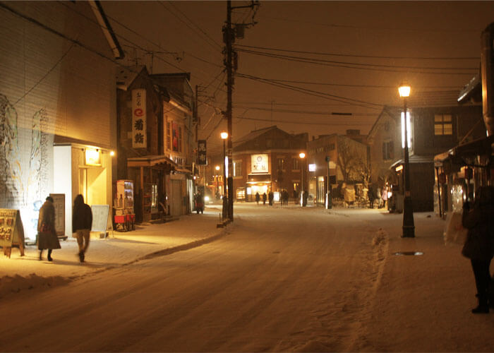 Snowy Otaru village being illuminated by street lamps.