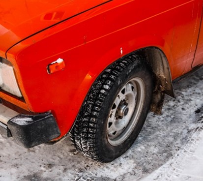 Red car with studless snow tires in the snow.